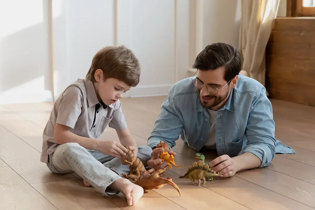 Un père et son fils jouant avec des dinosaures en plastique